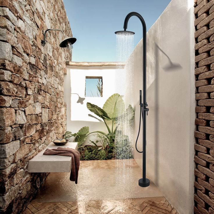 a bathroom with a shower head and hand held shower faucet next to a brick wall