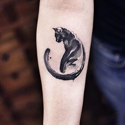 a black and white photo of a cat in a circle tattoo on the right forearm