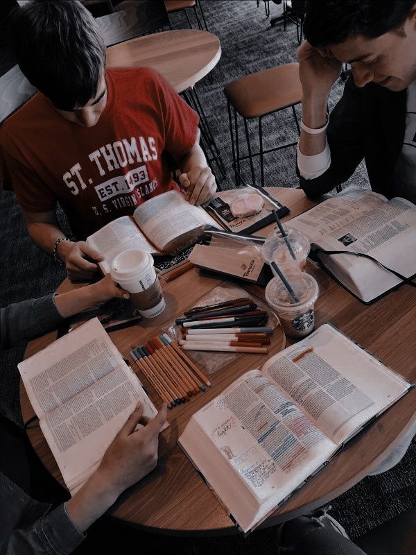 two people sitting at a table with open books