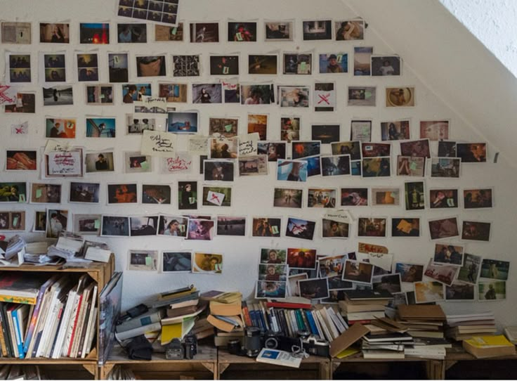 a room filled with lots of books and pictures on the wall next to a desk