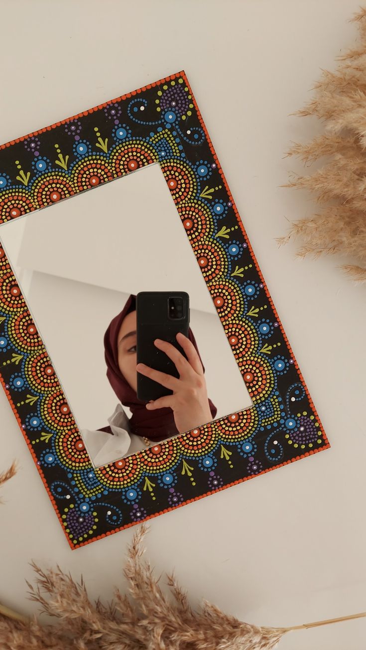 a woman taking a selfie with her cell phone in front of a decorative mirror