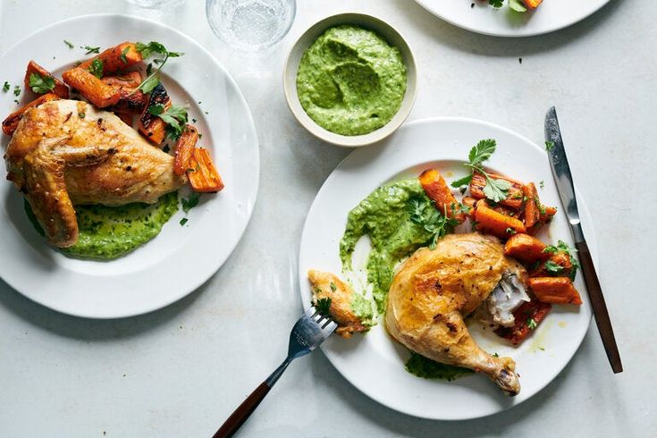 three white plates topped with chicken and veggies next to silverware on a table