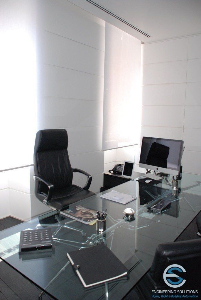 an office with a glass desk and black leather chair in front of the computer monitor