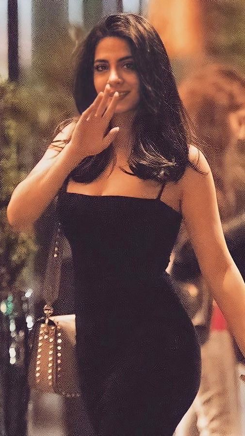 a woman walking down the street with her hand in her mouth and wearing a black dress