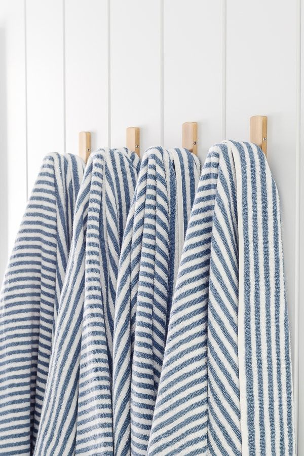 three blue and white striped towels hanging from hooks on the wall next to each other