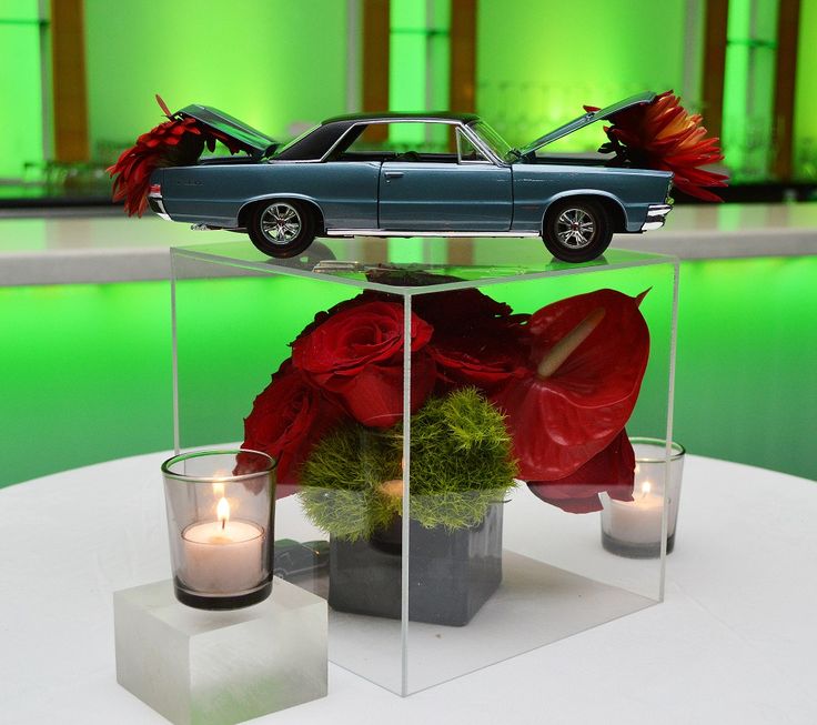 a car is sitting on top of a table with flowers and candles in front of it