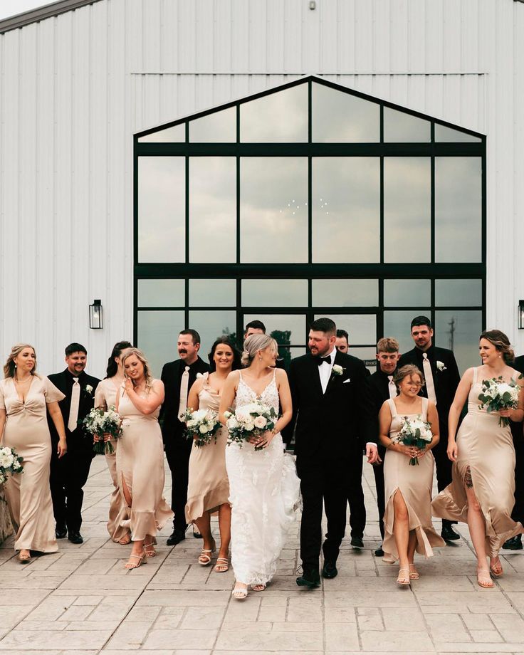 a large group of people standing in front of a building with flowers and dresses on