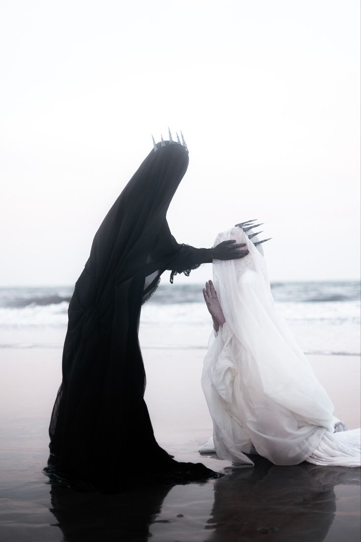 two women dressed in black and white on the beach