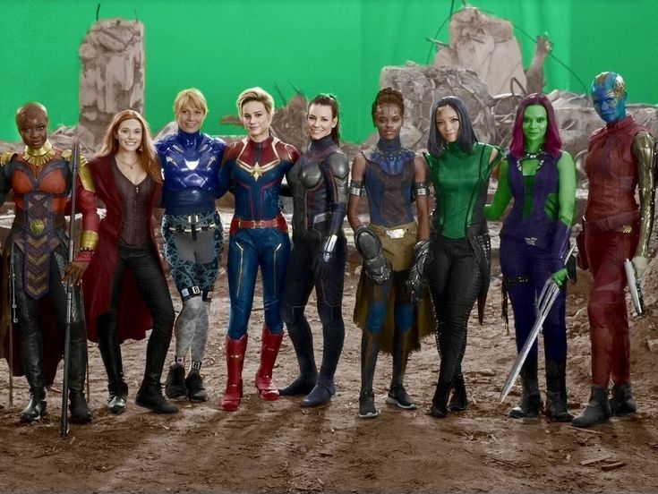 a group of people standing next to each other in front of a green screen background