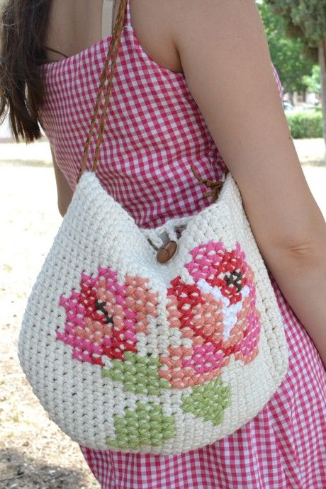 a woman carrying a white purse with pink flowers on the front and side, while wearing a red gingham dress