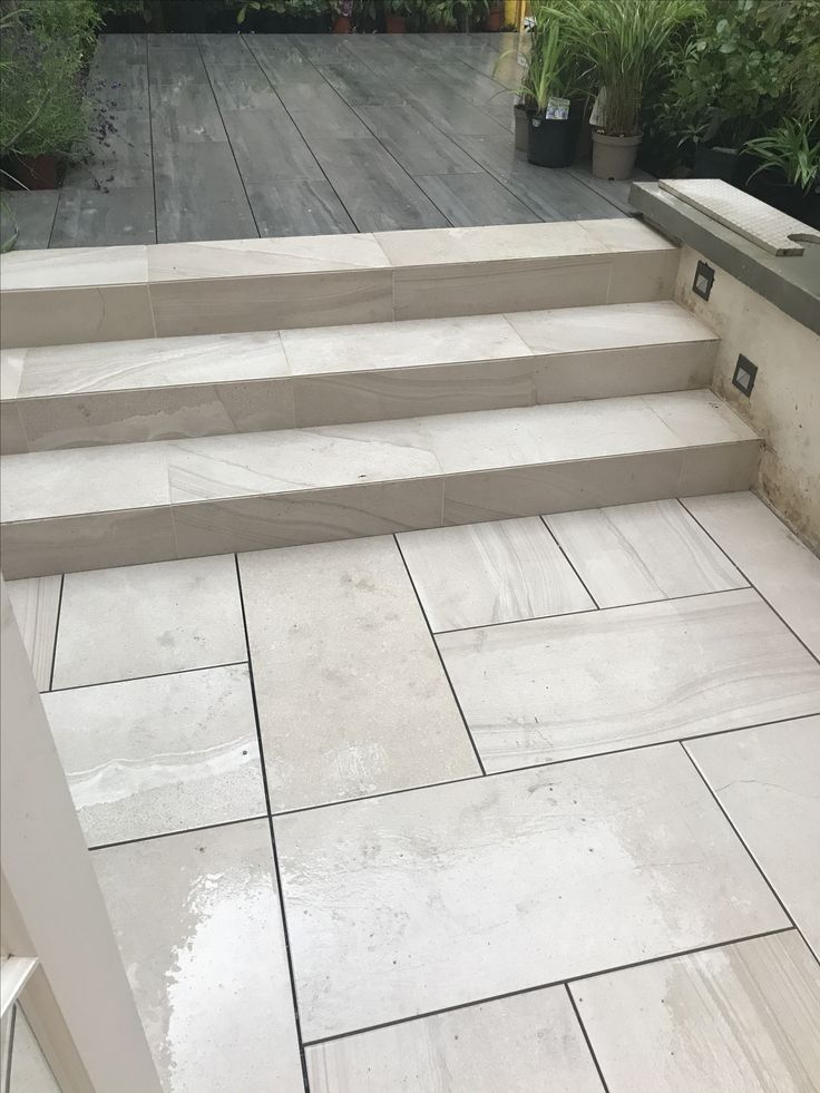 a patio with steps and plants in the background