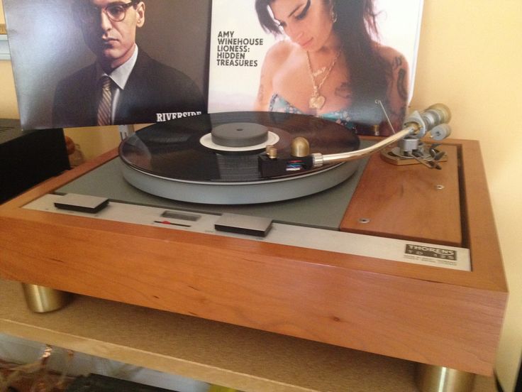 an old record player is sitting on top of a wooden table next to a movie poster