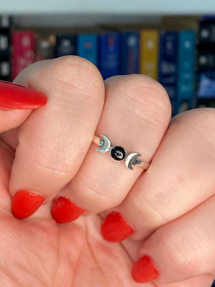 this is asterling silver ring that has a small onyx stone in the center and depicts the moon phases. Black Sterling Silver Moon Phase Jewelry, Black Sterling Silver Jewelry With Moon Phase, Black Sterling Silver Birthstone Rings, Black Sterling Silver Rings With Birthstone, Black Moon-shaped Jewelry With Sun And Moon Design, Black Moon Jewelry With Sun And Moon Design, Black Moon-shaped Sun And Moon Jewelry, Black Symbolic Adjustable Rings, Adjustable Black Symbolic Rings