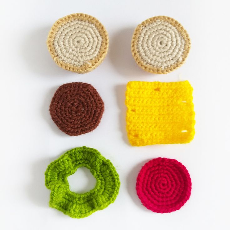 four crocheted objects are arranged on a white surface, including one circle and two circles