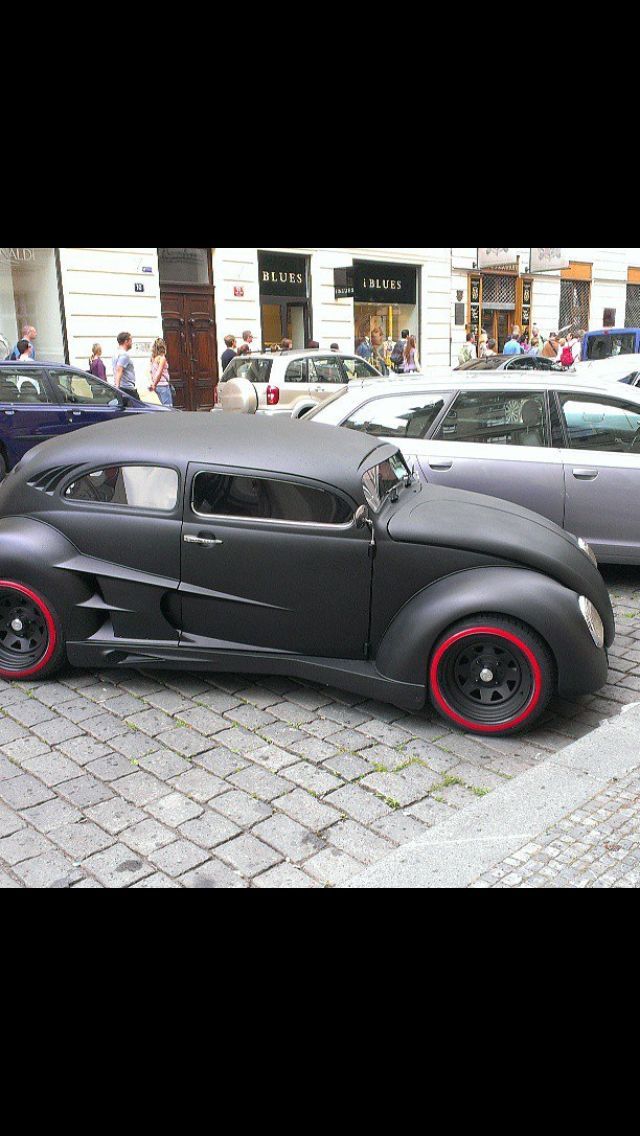 an old black car parked on the side of a street