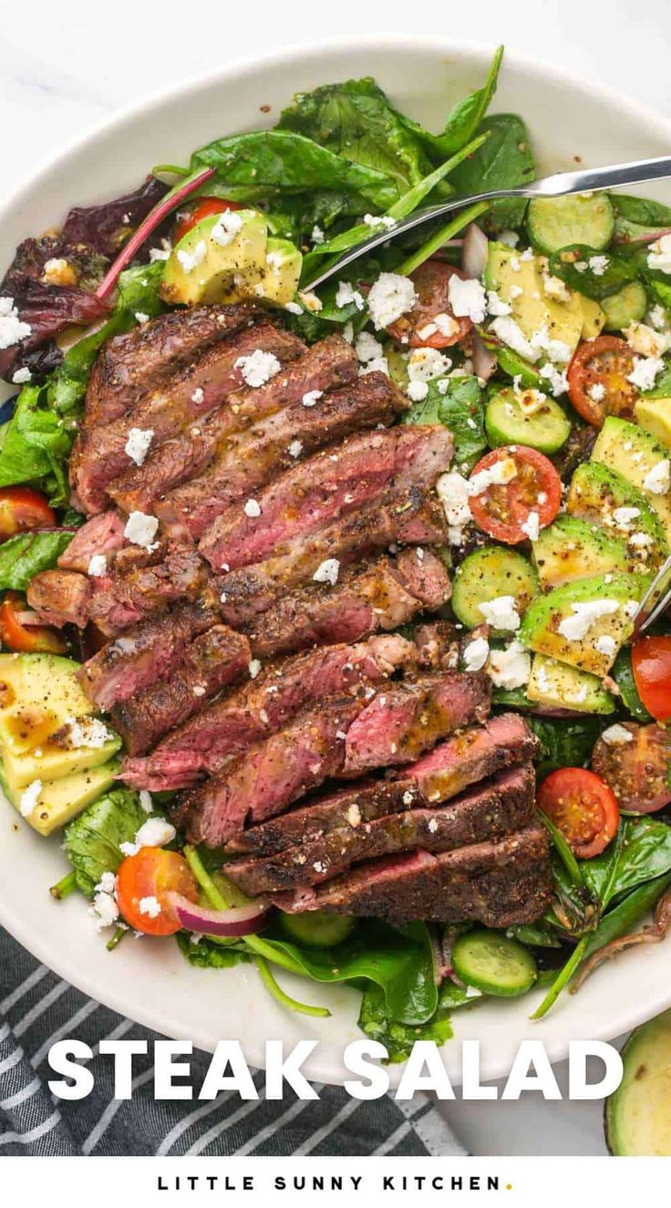 steak salad with cucumbers, tomatoes and feta cheese in a white bowl