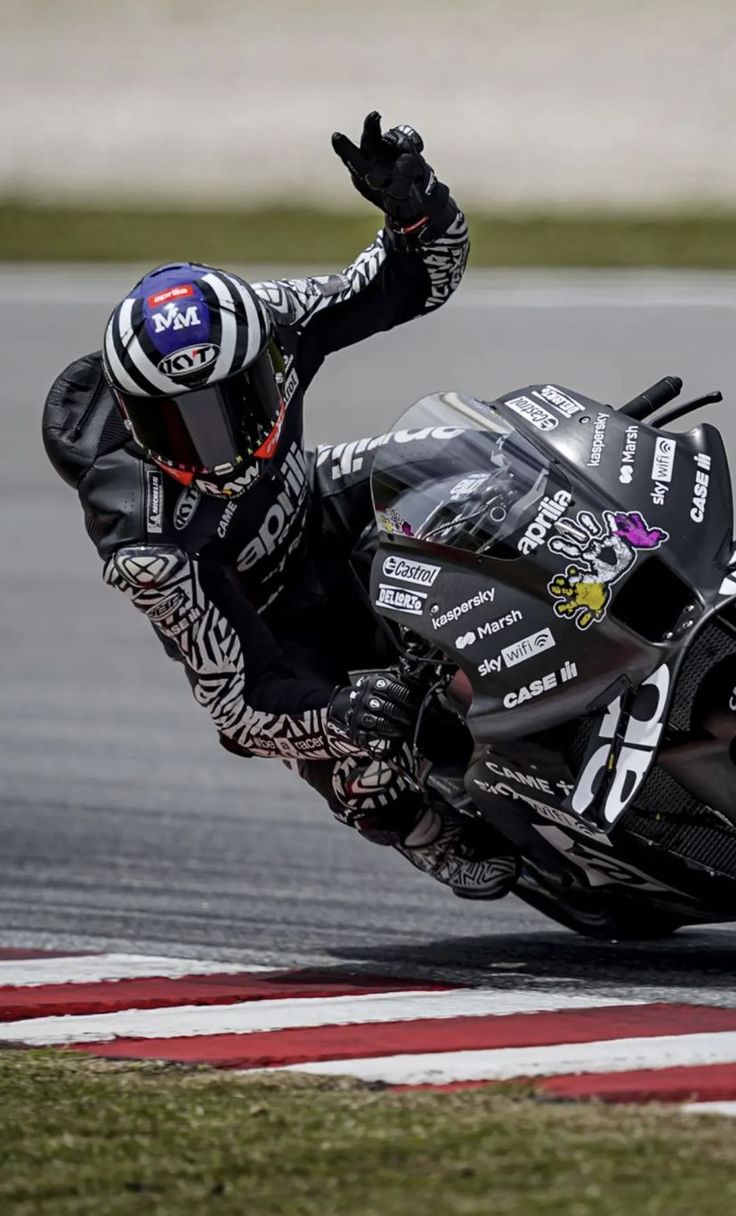 a man riding a motorcycle on top of a race track with his hand in the air