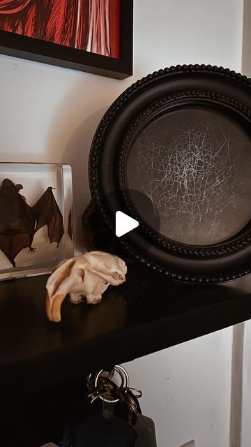 a black plate sitting on top of a wooden table next to a glass vase and other items