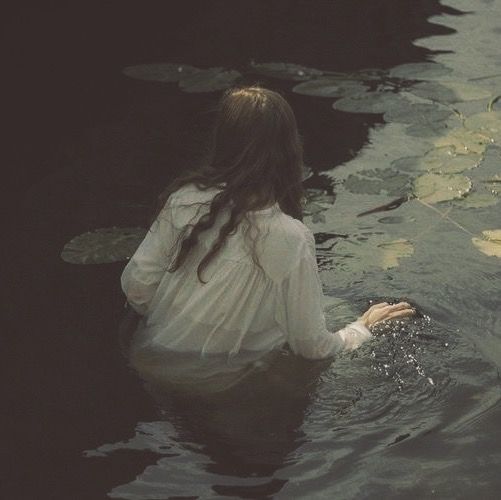 a woman sitting in the water with her hands on her knees