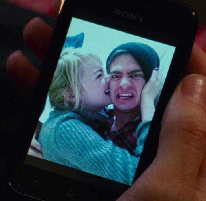 a person holding up a cell phone to take a photo with the screen showing an image of a man kissing a woman