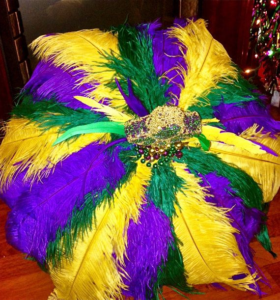 a large purple, yellow and green feather pillow on a wooden floor next to a christmas tree