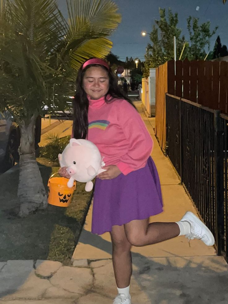 a girl in a pink shirt and purple skirt holding a stuffed animal