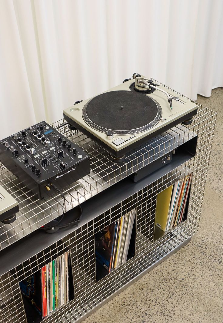 two turntables sitting on top of a metal shelf next to books and cds