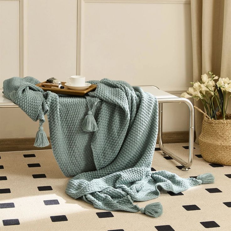 a teal blanket sitting on top of a floor next to a basket with flowers