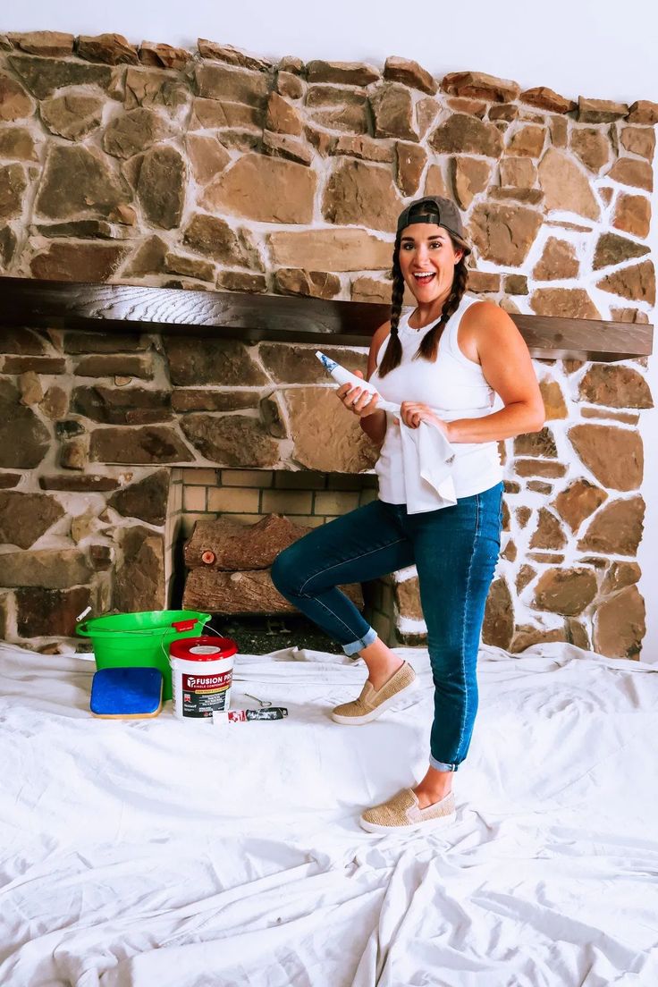 a woman standing on top of a bed in front of a stone wall and fireplace