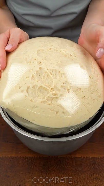 a person holding a bowl with dough in it