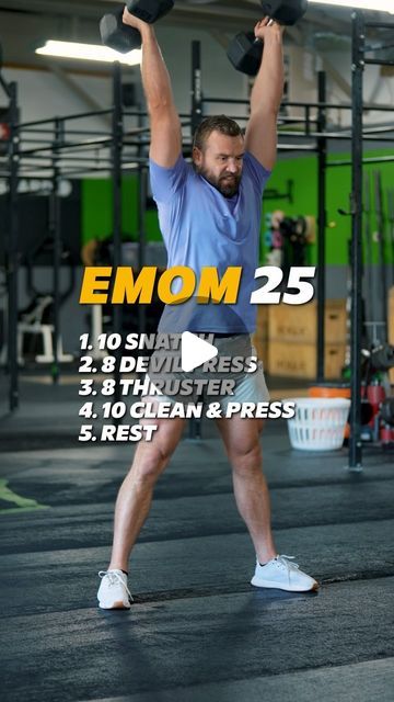 a man holding two dumbs in the middle of a crossfit gym area