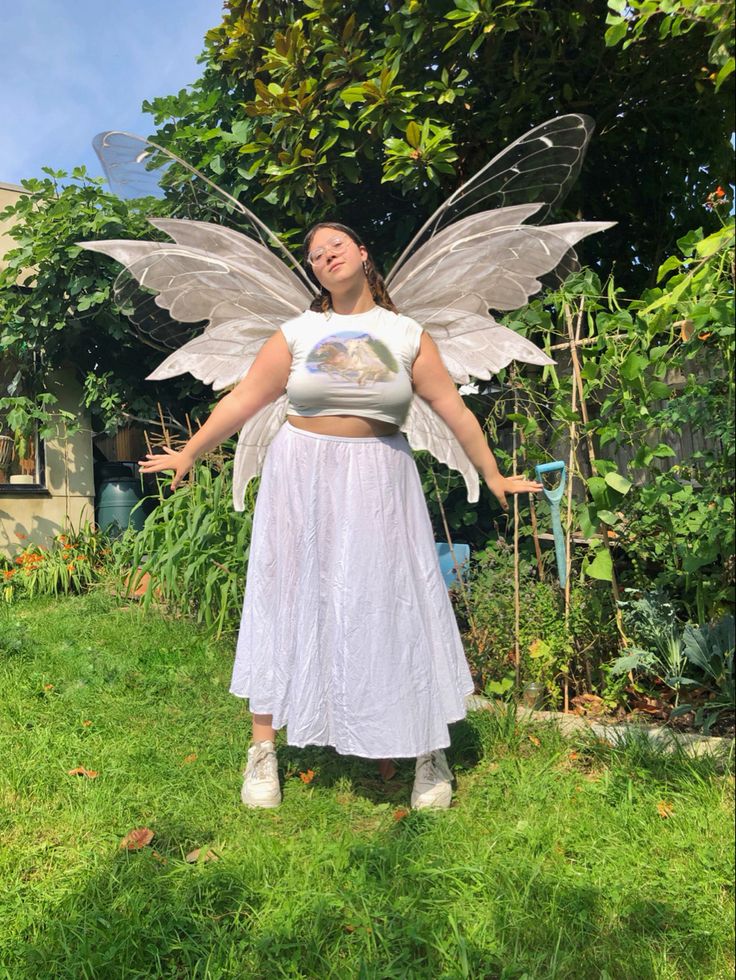 a woman dressed as a fairy standing in the grass