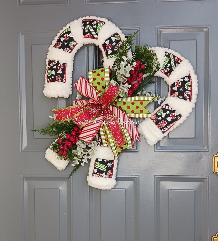 a christmas wreath on the front door decorated with stockings and stocking hanging from it