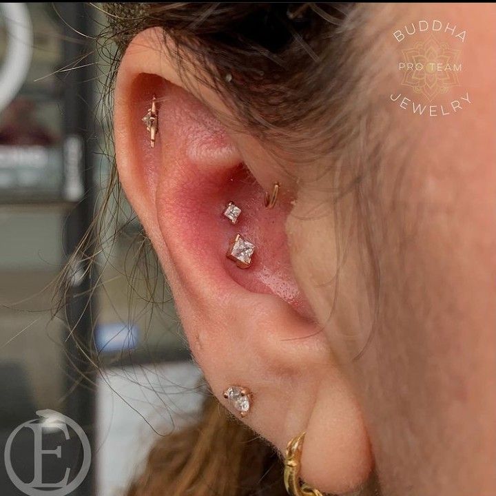 a close up of a person's ear with three piercings on top of it