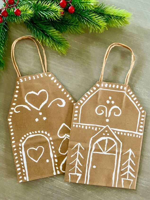 two brown bags with white designs on them sitting next to a christmas tree and decorations