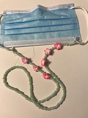 a surgical mask with pink flowers on it and a lanyard attached to the strap