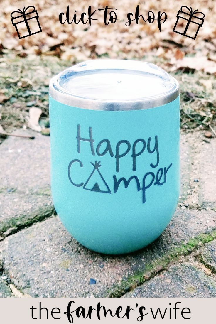 a blue cup with the words happy camper written on it sitting in front of some leaves