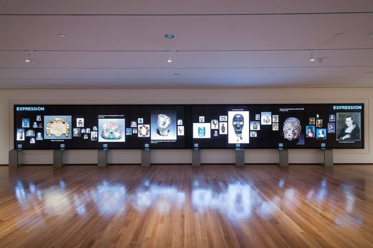 an empty room with wooden floors and multiple displays on the wall