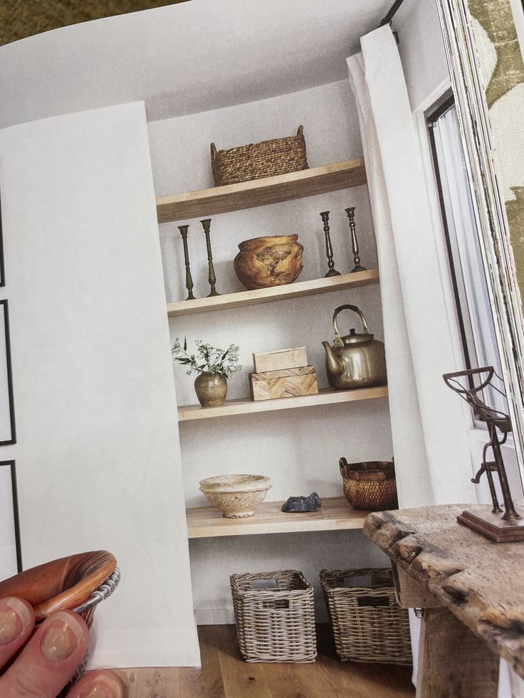 a person holding a knife in front of a book shelf filled with pots and bowls