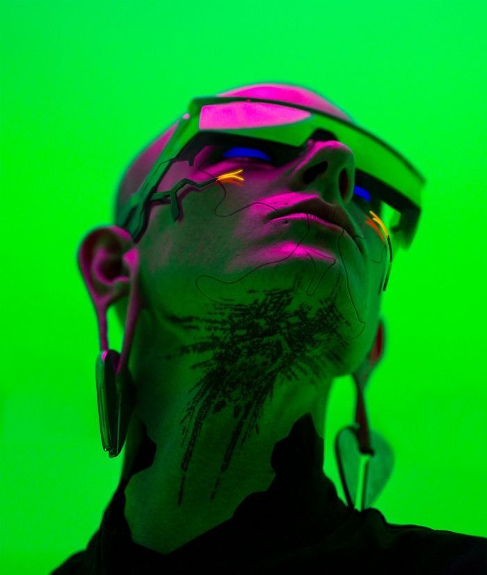 a man with his face painted in neon colors wearing headphones and looking off to the side