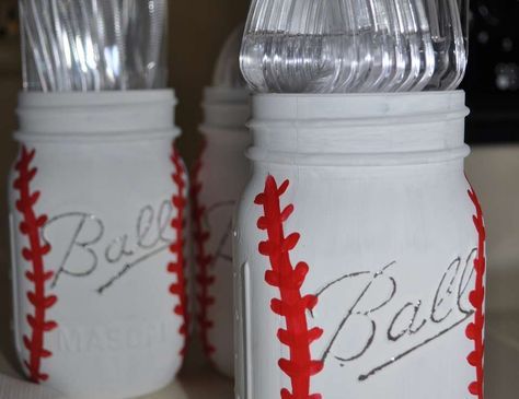 three white mason jars with silver lids and baseball stitching on the side, one has metal forks in it