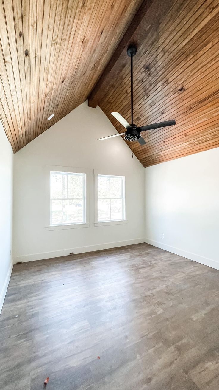 an empty room with wood ceiling and white walls