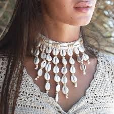 a close up of a woman wearing a necklace with shells on it and pearls attached to the neck