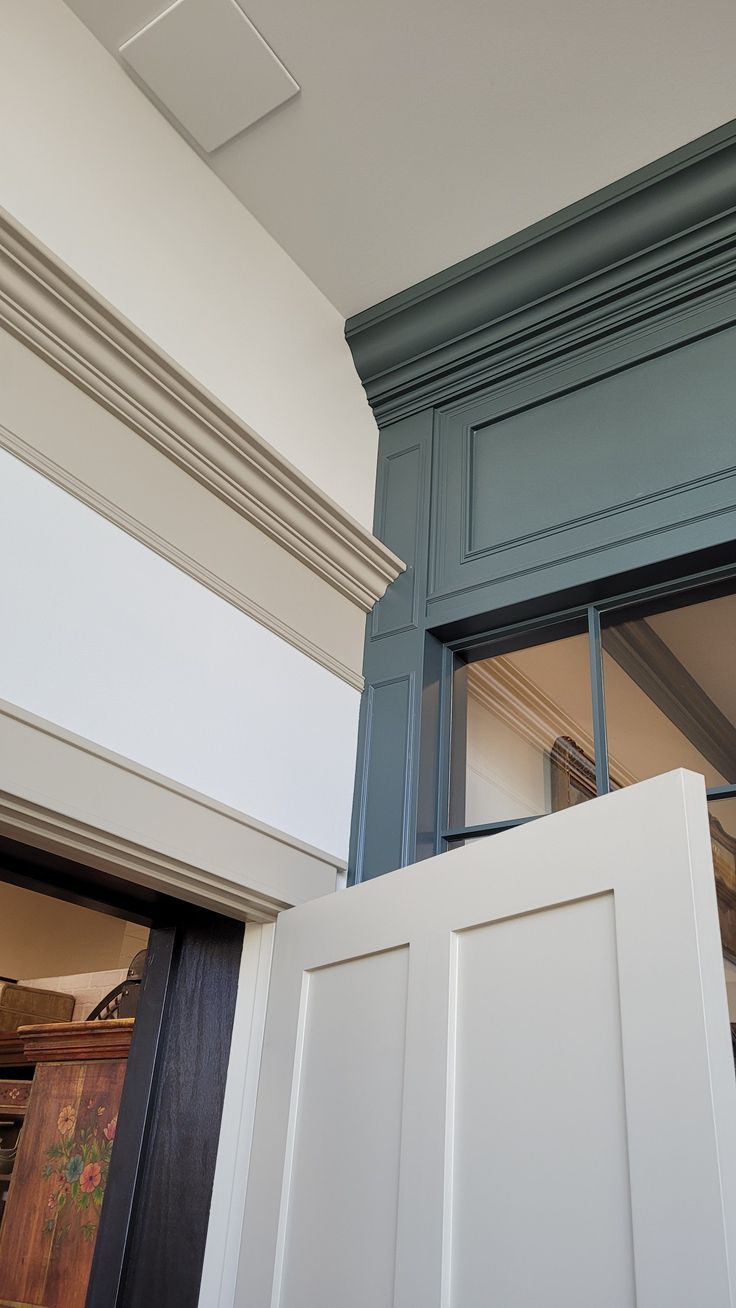 the inside of a kitchen with blue painted cabinets and white trim on the door frame