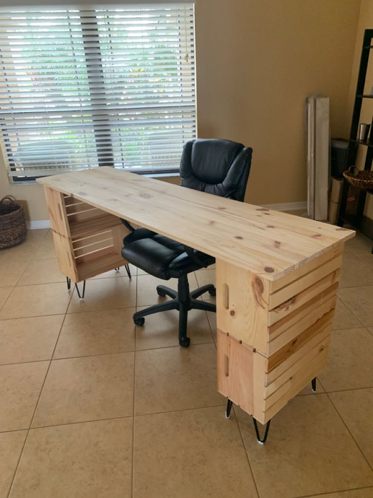 an office desk made out of pallet wood with a chair next to it in front of a window