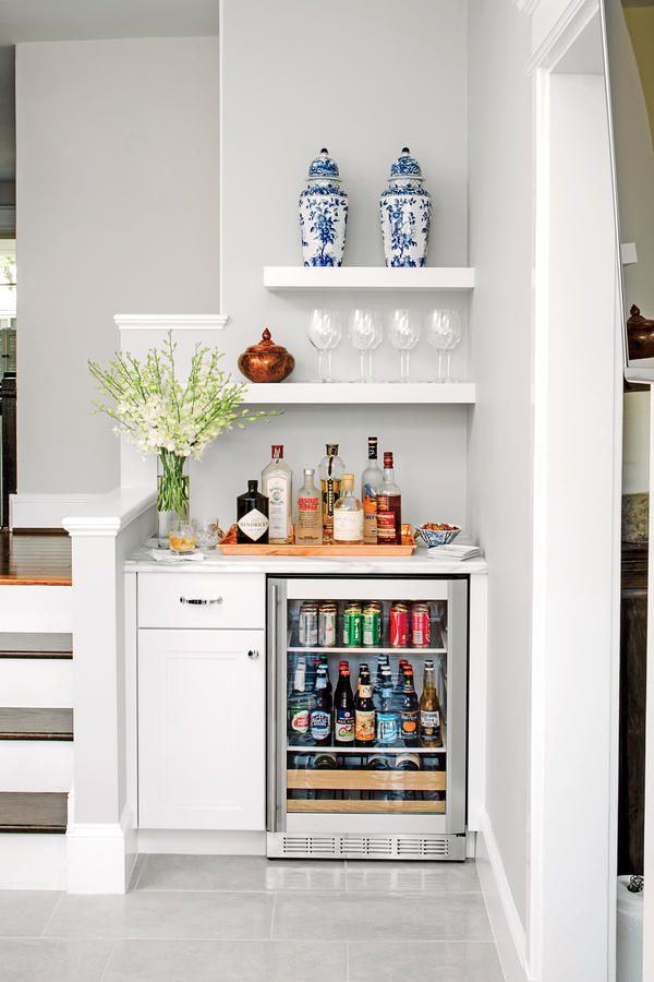 an open refrigerator with drinks in it next to some stairs and white cabinets on the wall