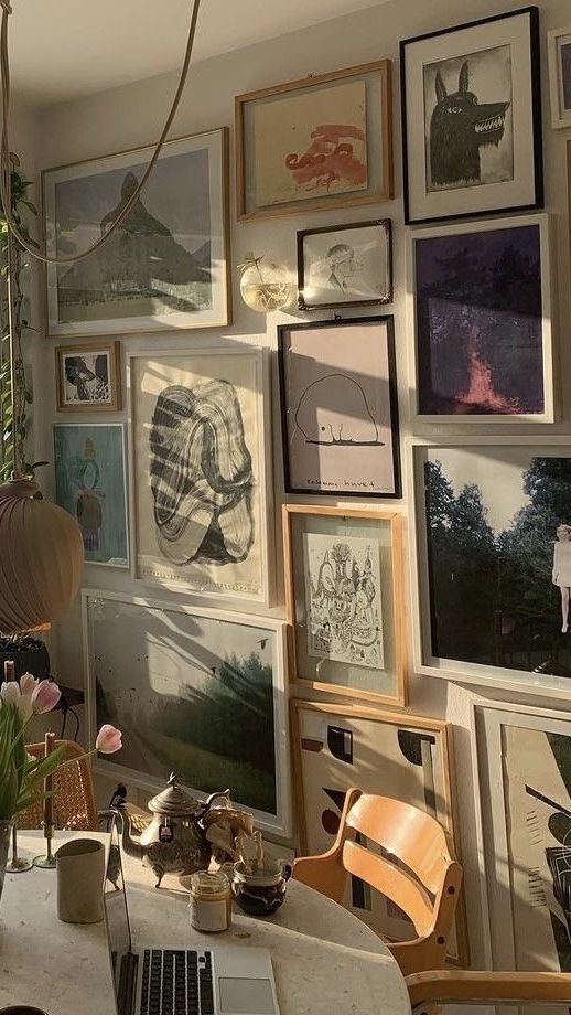 a room filled with lots of framed pictures on the wall and a laptop computer sitting on top of a table