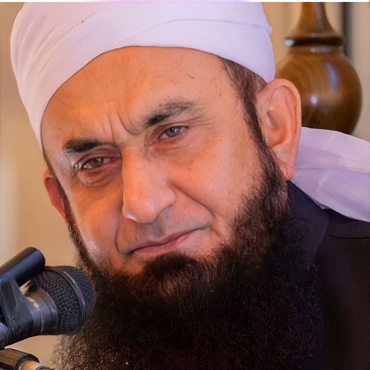 a close up of a person with a microphone in front of him and wearing a white turban