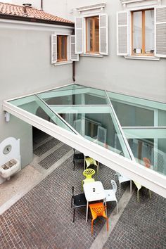 an overhead view of a patio with tables and chairs in front of the building's windows