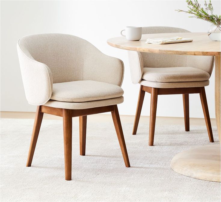 two chairs sitting next to each other in front of a table with a cup on it